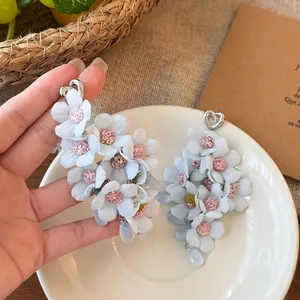 Close-up detail of blue and pink fabric flower tassel earrings with heart-shaped hooks