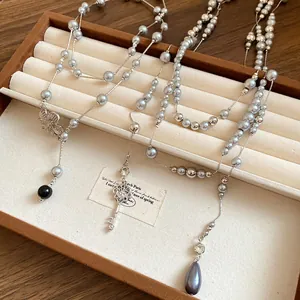 Detailed close-up of elegant silver-toned beaded pearl necklaces with key and flower charms