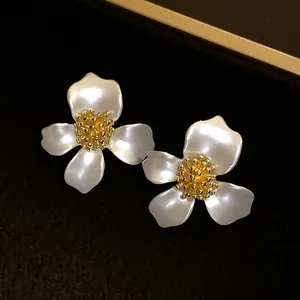 Primo piano macro di orecchini vintage a fiore bianco francese con centro dorato