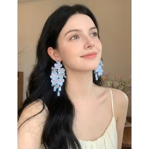 Detailed view of elegant light blue fabric flower tassel earrings worn by an Asian model