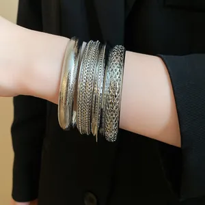 Primo piano di bracciali rigidi in metallo argento con trame vintage e motivi intrecciati