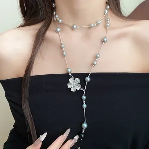 Close-up of elegant grey pearl necklace with a sparkling rhinestone flower pendant.