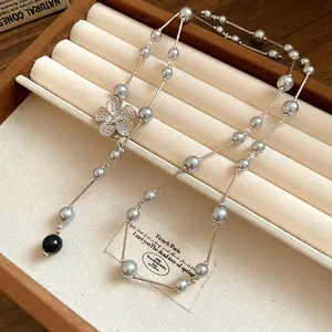 Macro view of grey pearl necklace with a sparkling crystal flower charm on velvet