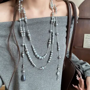 Elegant multi-layer grey pearl necklace with sparkling flower pendant on grey sweater