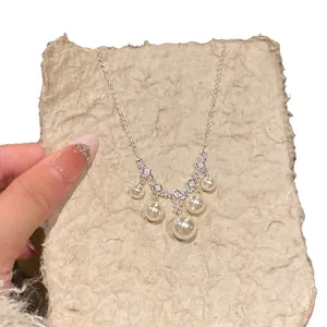 Elegant French-style silver necklace featuring square zirconia and graduated pearls on texture