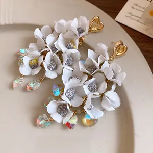 Close-up of elegant white fabric flower earrings with sparkling heart crystals