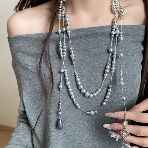 Detail of multi-layer necklace with grey pearls, silver beads, and rhinestone flower charm.