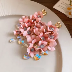 Close-up detail of pink fabric flower earrings with iridescent heart crystal drops