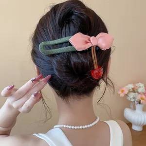 Close-up showing an elegant pink bow hair clip with a red resin cherry on a bun.