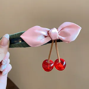 Detail view of exquisite fabric pink bow and red resin cherry duckbill hair clip