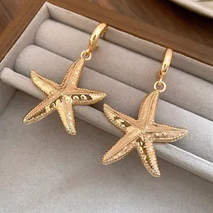 Elegant gold-plated starfish pendant earrings displayed in a vintage jewelry box