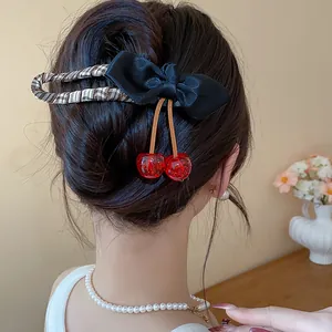 Detailed view of a chic black fabric bow hair clip featuring realistic red resin cherries
