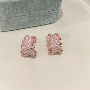 Detailed view of pink enamel C-shape earrings with inlaid cubic zirconia crystals