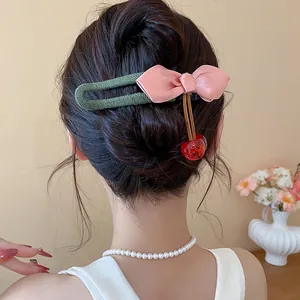 Close-up detail of a handmade fabric pink bow and resin cherry hair clip on styled dark hair