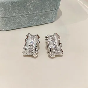Detailed macro shot of silver pleated C-shaped earrings featuring rows of square zircons