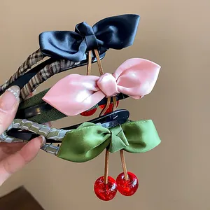 Close-up detail of stylish fabric bow hair clips featuring vibrant resin cherry charms