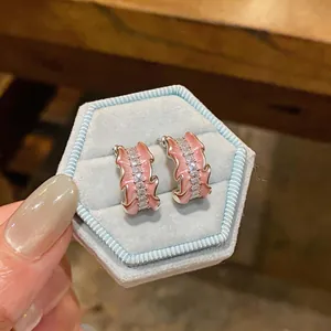 Detailed macro view of pink enamel C-shaped hoop earrings with sparkling zircon stones