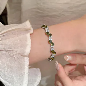 Detailed view of a silver zircon bracelet featuring oval green stones on a model's wrist
