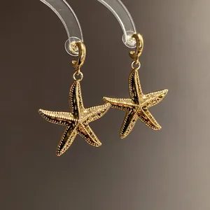 Close-up of vintage gold starfish drop earrings featuring intricate textured surface details.