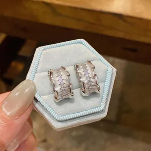 Detailed macro view of silver pleated C-shaped earrings accented with shimmering zircon stones