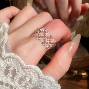 Vista dettagliata di un anello intrecciato a mano con perle di vetro oro rosa e bianche