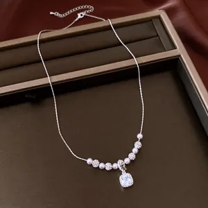 Close-up of elegant pearl necklace featuring a square zircon pendant in jewelry box.