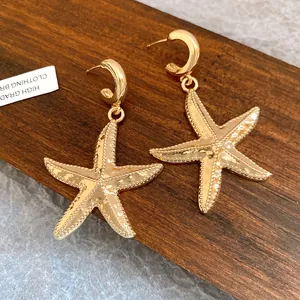 Detailed macro view of vintage gold starfish pendant earrings on wood