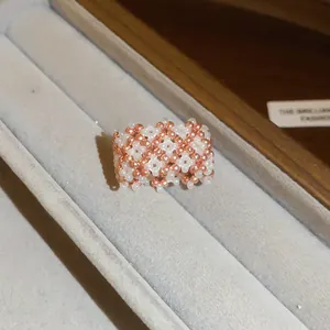 Primo piano di un anello di perline fatto a mano in oro rosa e bianco in un espositore.
