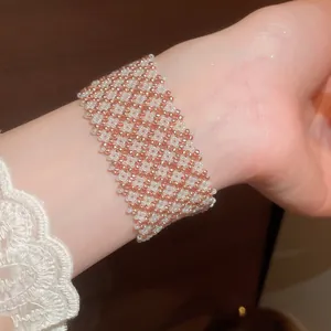 Squisito primo piano di un braccialetto in maglia di perle di vetro oro rosa e bianco