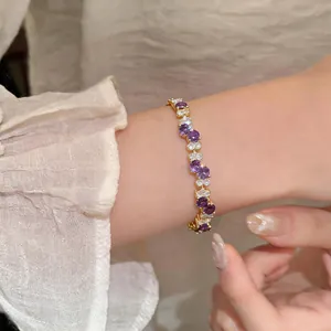 Detail shot of a gold-plated bracelet with purple and white zircon stones on a wrist