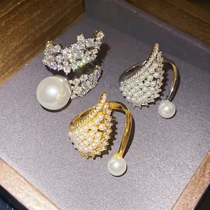 Elegant zircon wing and pearl open rings set displayed in a classic wooden jewelry box