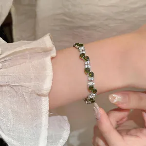 Elegant close-up of a vintage bracelet with green and clear zircons on a woman wrist