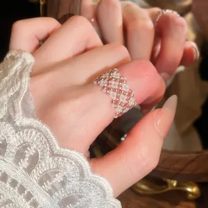 Primo piano di un anello fatto a mano con perline bianche e oro rosa con manica in pizzo