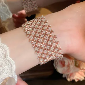 Primo piano del bracciale magnetico intrecciato con perle di vetro oro rosa e bianche