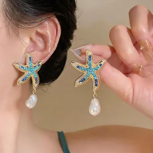 Macro detail of summer starfish earrings with blue rhinestones and elegant baroque pearls