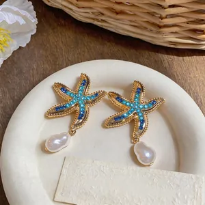 Close-up detail of luxury starfish stud earrings featuring blue rhinestones and pearls