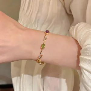 Detailed view of an elegant vintage gold bracelet with purple and green zircon stones on a wrist