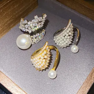 Detailed view of three luxury wing-shaped open rings with pearls and zircons in a jewelry box