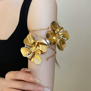 Détail d'un brassard doré en forme de fleur avec une texture métallique sur le bras.