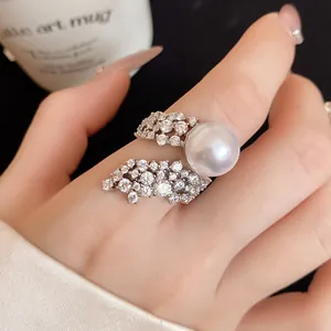 Macro detail view of a refined pearl ring featuring sparkling zircon wings on a hand