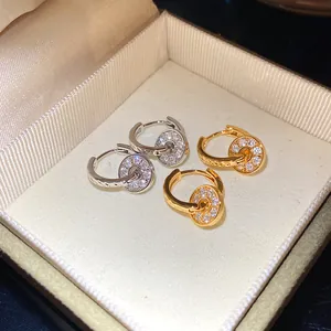 Detail of refined double hoop earrings with sparkling crystal-set charms in a box.