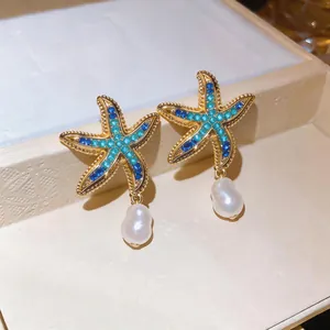 Close-up of starfish earrings with blue rhinestones and dangling white pearls.
