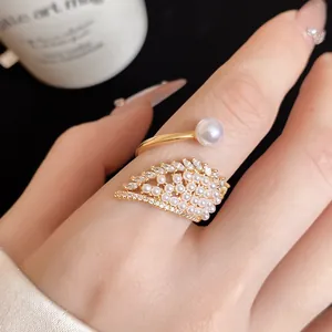 Exquisite close-up of a gold-finish wing ring with pearls and sparkling zircons.