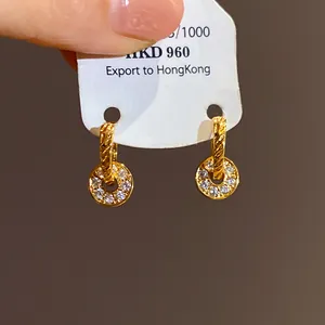 Detailed macro view of gold-tone hoop earrings with sparkling pave-set crystal charms
