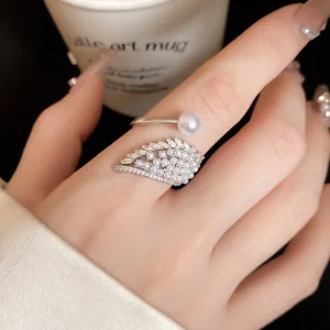 Close-up detail view of elegant silver wing ring with pearls and shiny zircon stones