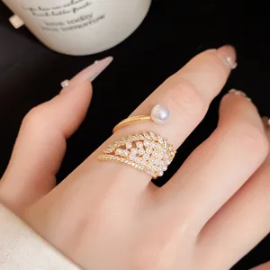 Detailed view of gold wing-shaped ring with pavé zircons and white pearls