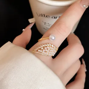 Macro view of an elegant gold wing ring featuring white pearls and pavé cubic zirconia