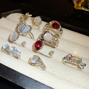 Detailed view of silver open rings set with iridescent resin stones and red gems