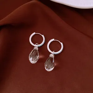 Elegant silver earrings with sparkling faceted crystal waterdrop pendants on brown silk.