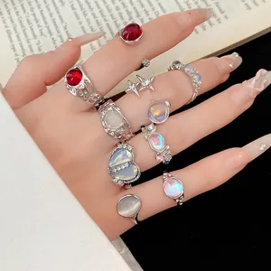 Nine-piece set of silver-tone rings with rhinestones and iridescent resin stones on hand.
